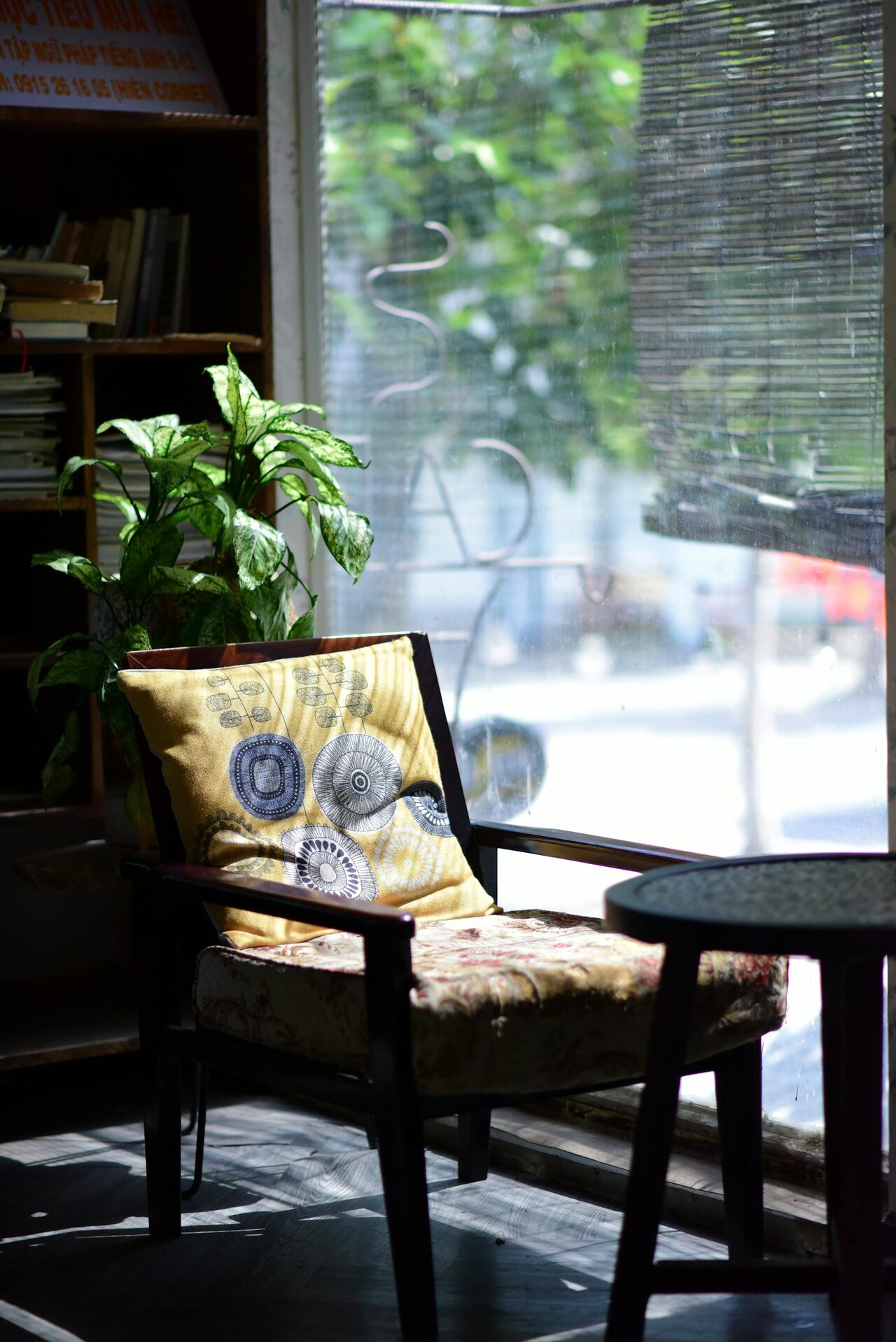 Sunlit corner with an armchair, plant, and small table beside large windows